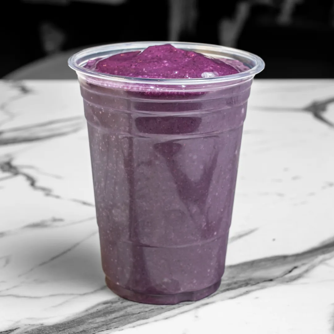 A Boo Berry smoothie in a clear plastic cup on a white marble table