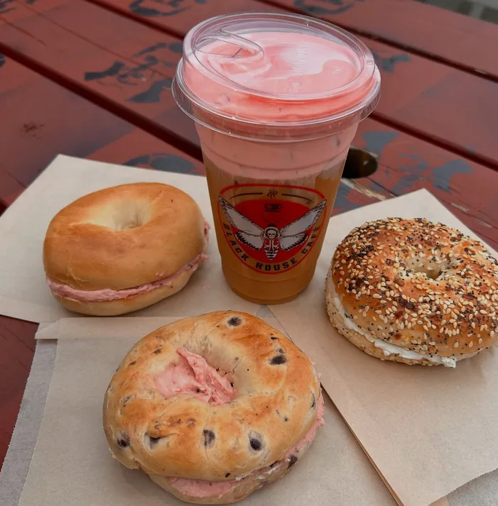 Breakfast bagel sandwiches and an iced drink on a red table at Black House Café