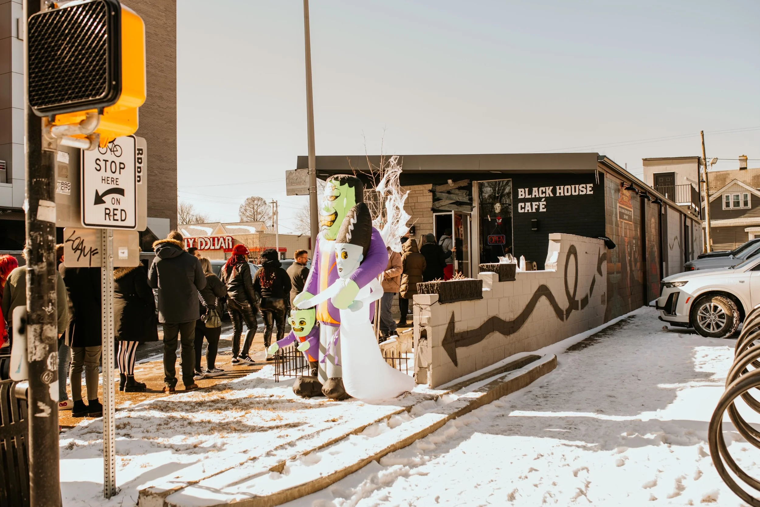 Winter exterior of Black House Café with an inflatable Bride of Frankenstein display and a crowd gathered outside the storefront, Fountain Square Indianapolis