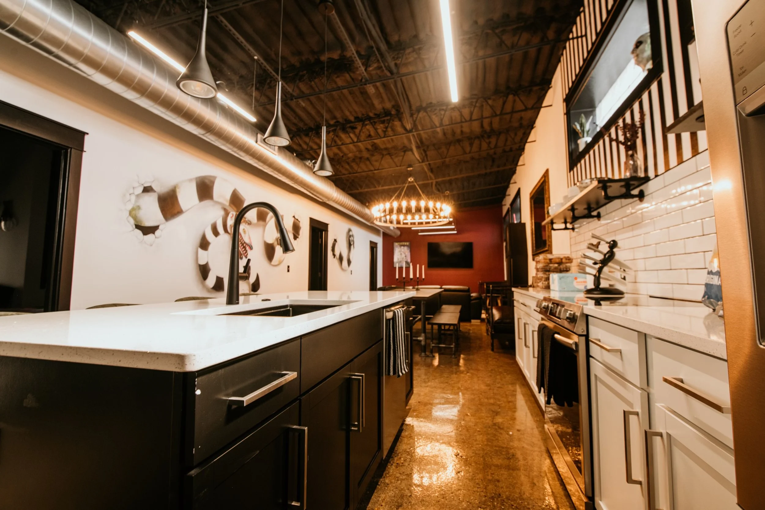 Interior kitchen and bar area at Black House Café with a quartz island, candelabra chandelier, and red accent wall, Fountain Square Indianapolis