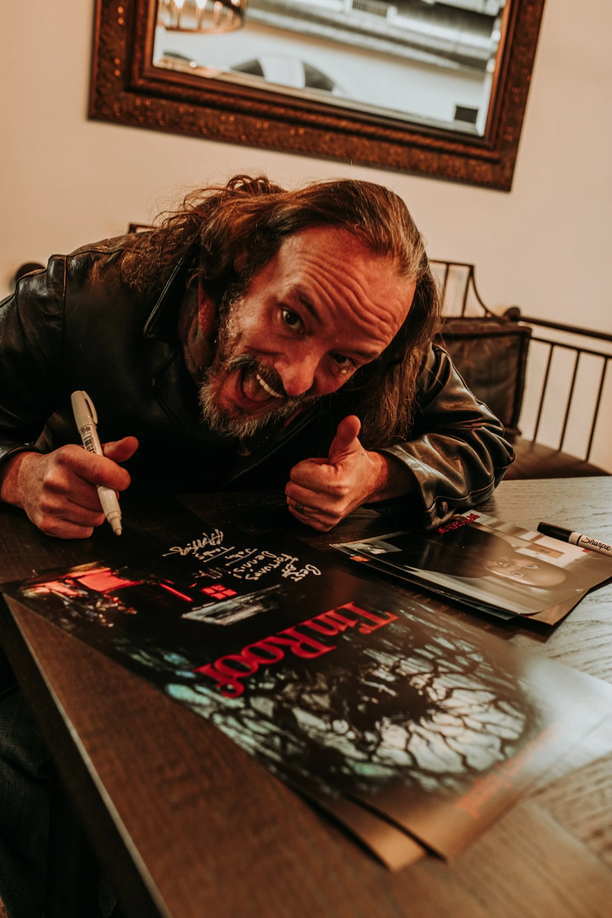 A guest signing a horror movie poster at an event inside Black House Café, Fountain Square Indianapolis