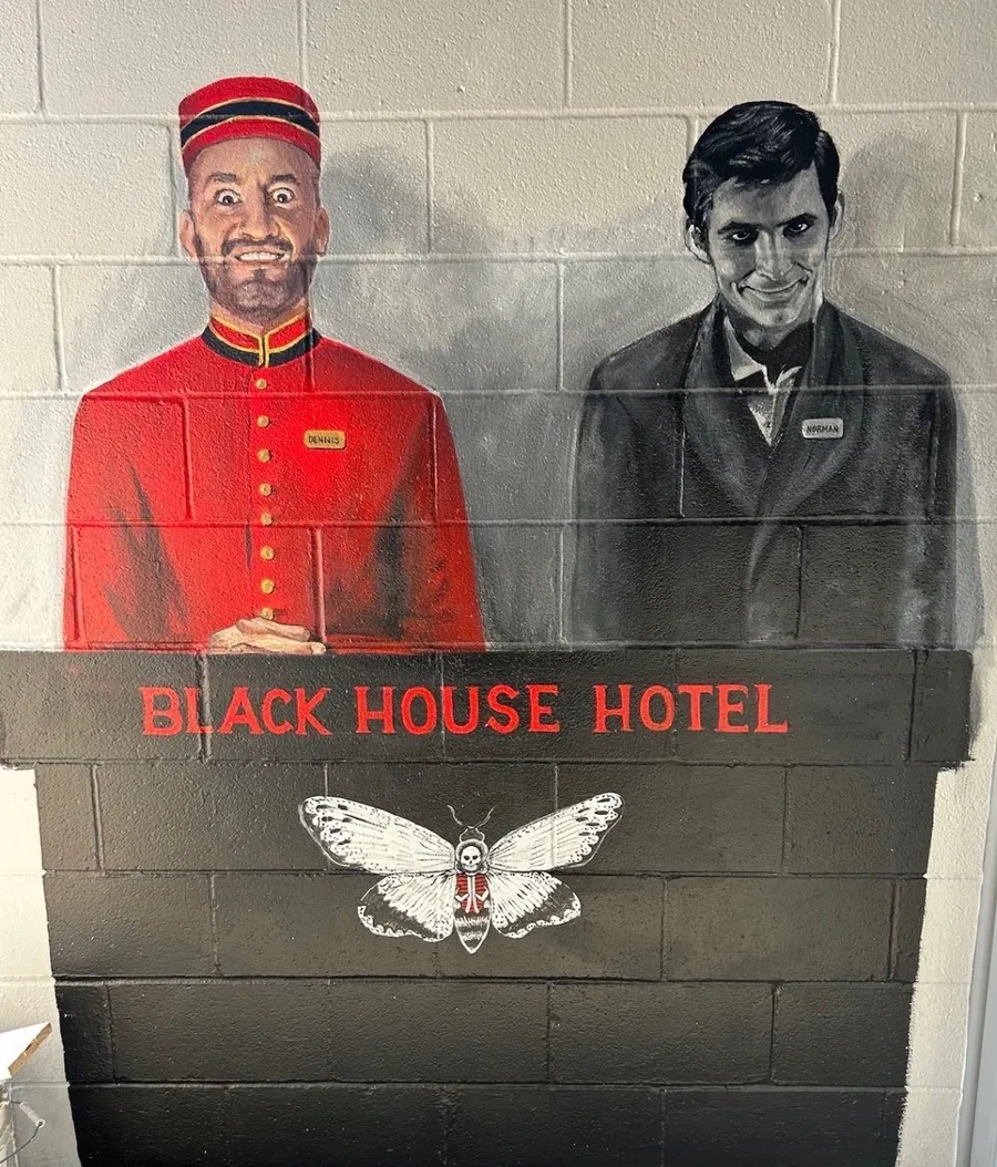 Hand-painted Black House Hotel mural: a bellhop and Norman Bates flanking a death's-head moth